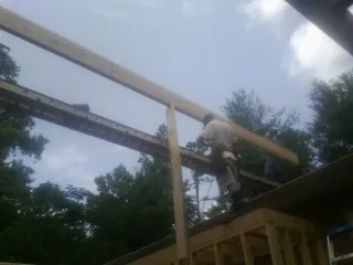Carpenter setting a ridge beam over a new addition frame — Ice Dam Removal by Roofing Brothers in Fair Play