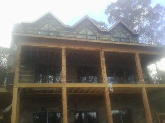 Dormers and porch framing on a large log home under construction — Roof Coating work by our crew in Fair Play