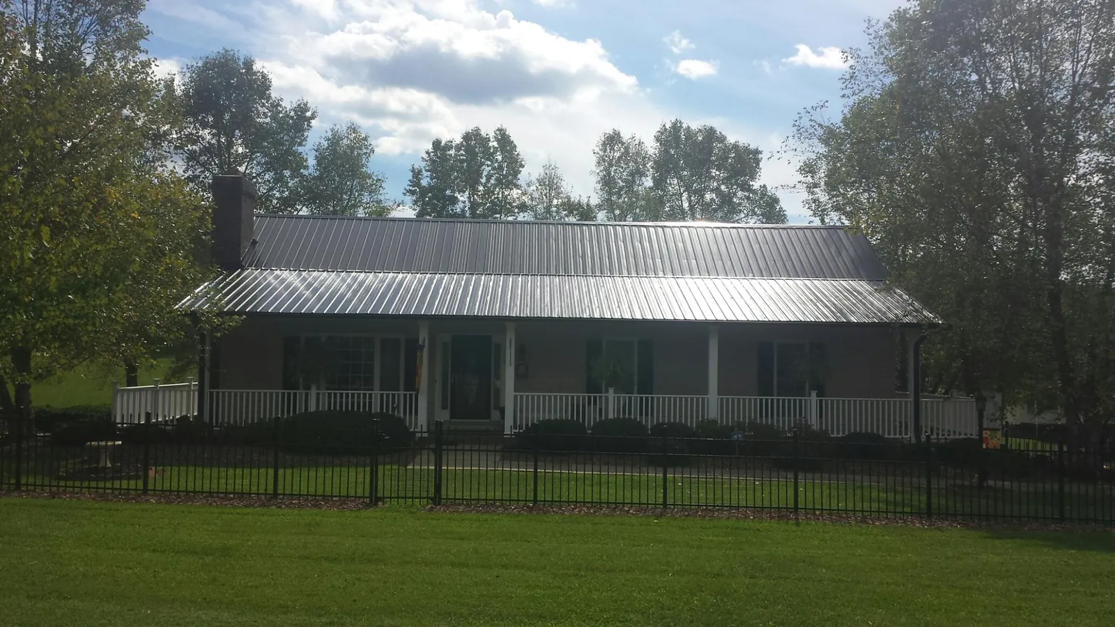 Gray metal roof on a brick ranch with a full width front porch — Gutter Guard Installation work by our crew in Fair Play