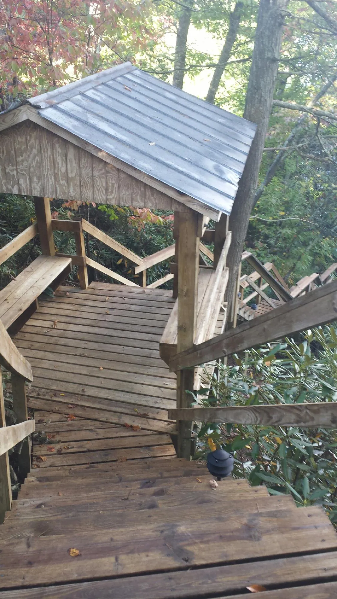 Metal roofed shelter over wooden steps on a wooded walkway — Skylight Repair & Installation work by our crew in Fair Play