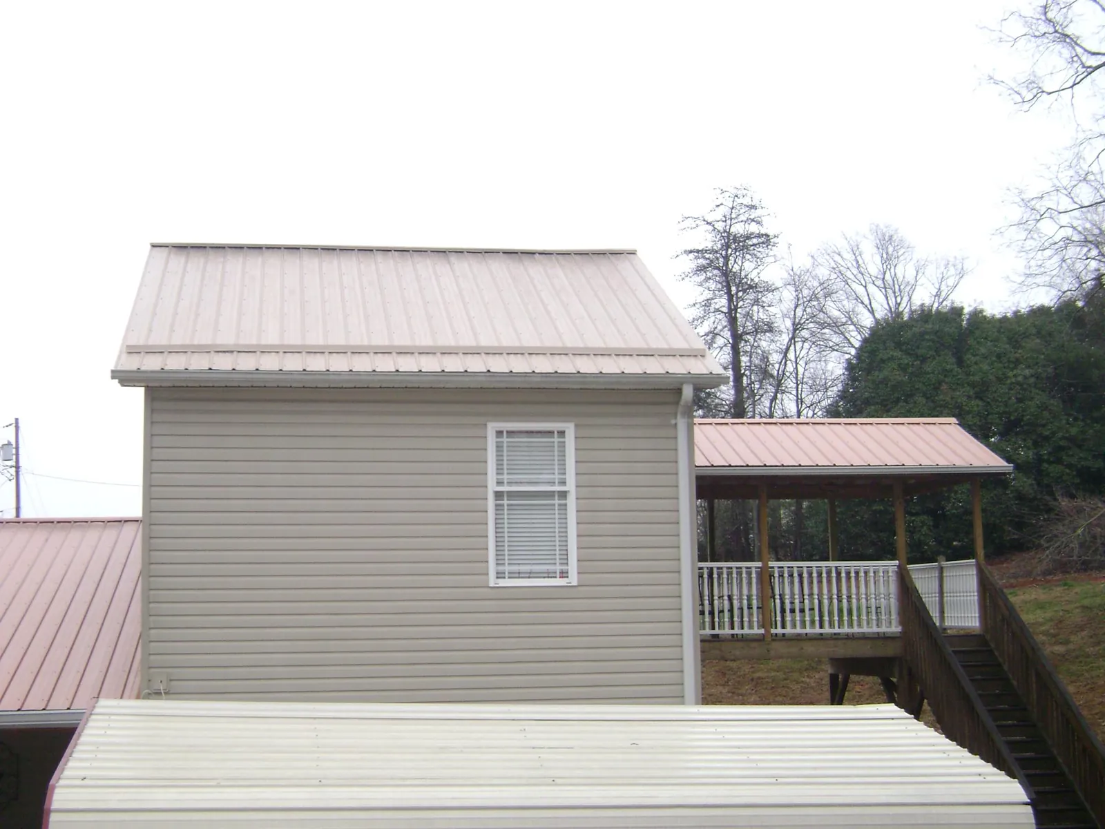 Tan metal roofs on a two story addition and attached porch, from a Roof Replacement job in Fair Play