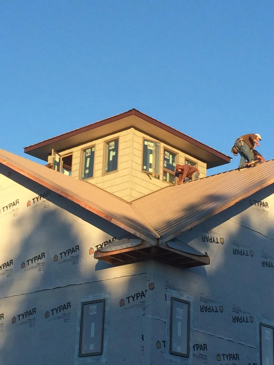 Roofers working around a rooftop cupola on a new metal roof at sunset — Roof Waterproofing in Fair Play by Roofing Brothers